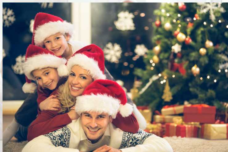 genitori e figli con cappelli di natale davanti all'albero